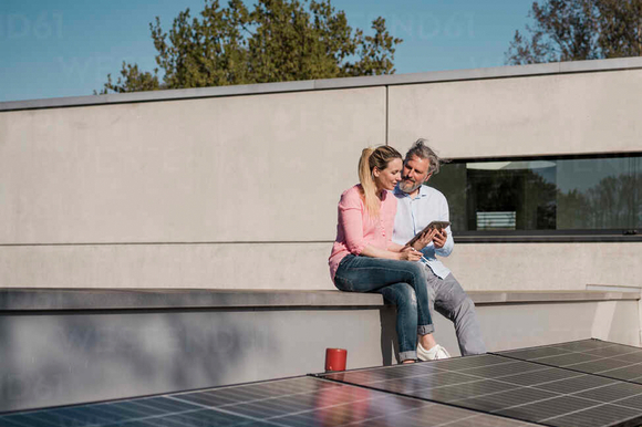 Ein paar bedient ein Tablet auf dem Dach mit Solarpanelen